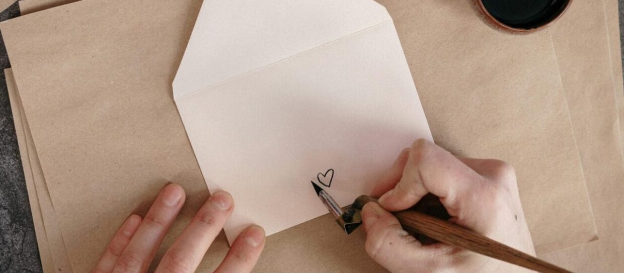 persona dibuja un corazón con tinta negra en el reverso de un sobre de papel para enviar cartas
