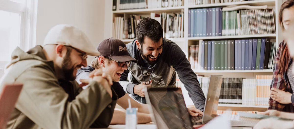Trabajadores en un hub ven pantallas de portátiles mientras rien