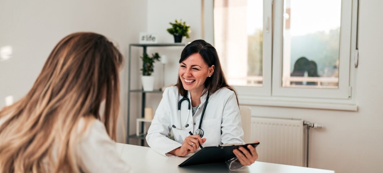 Medico Venezolano sonríe mientras atiende un paciende en la sanidad pública en España.