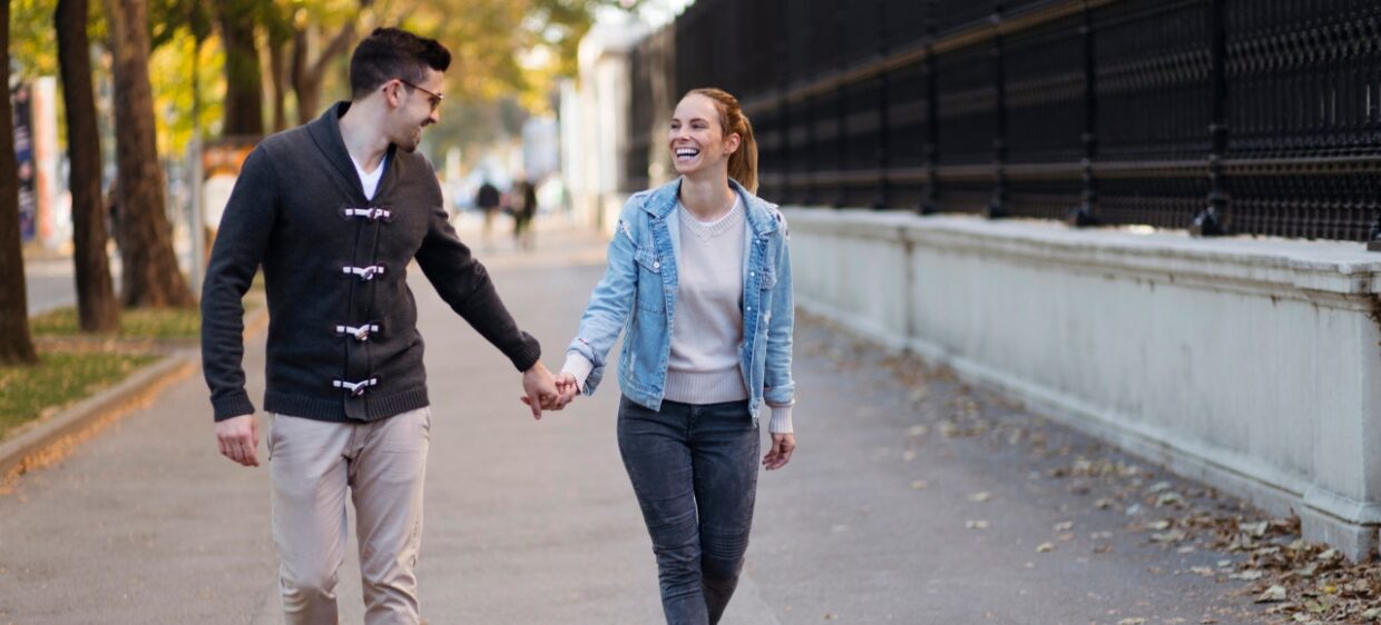 Pareja camina de la mano mientras sonrie en España