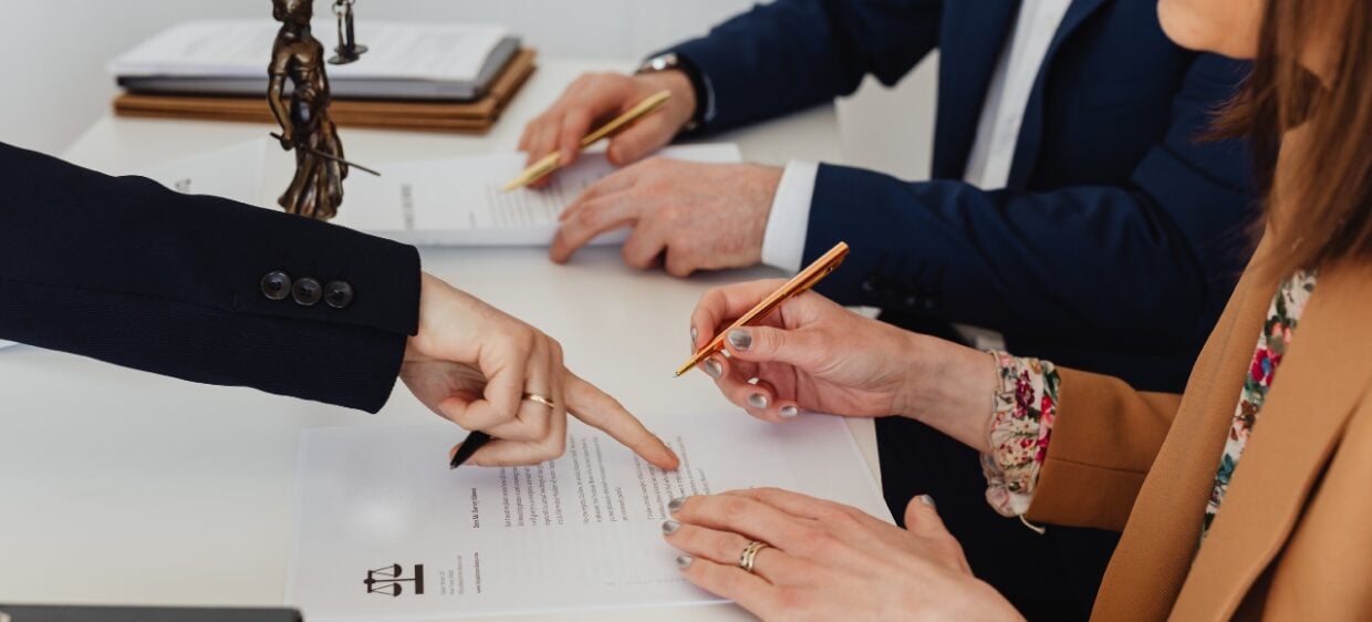 Dos personas ante un abogado, firmando un documento. Cambio de residencia por razones humanitarias en España